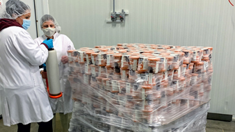 Two staff wearing Protective Equipment working on a pallet of food.